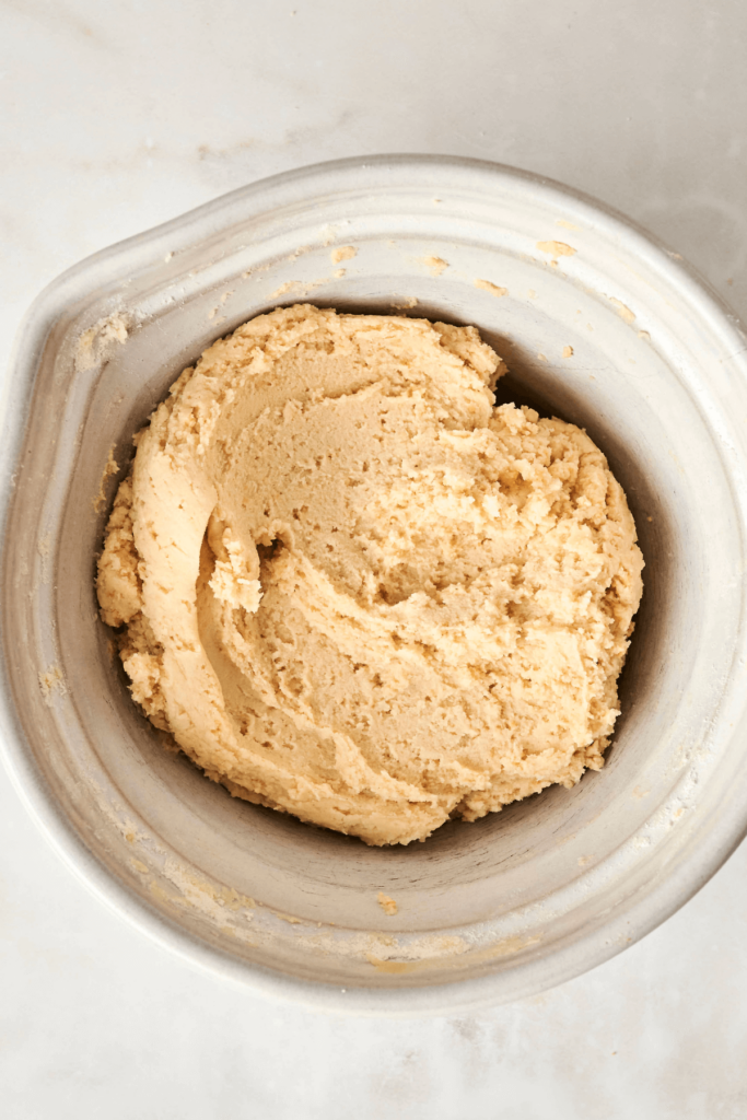 Un bol de mélange rempli de pâte à biscuits aux amandes lisse et crémeuse.