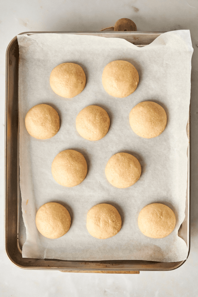 Biscuits Boule Neige aux Amandes dorés sortis du four, refroidissant sur une plaque de cuisson tapissée de papier sulfurisé avant leur enrobage de sucre glace.