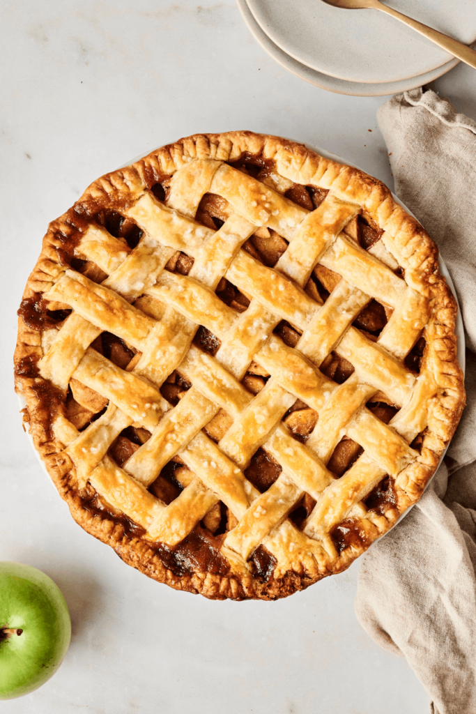 Tarte aux pommes dorée sur une surface blanche.