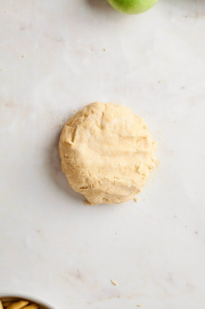 Smooth disc of pie dough on a floured surface, ready to be chilled.