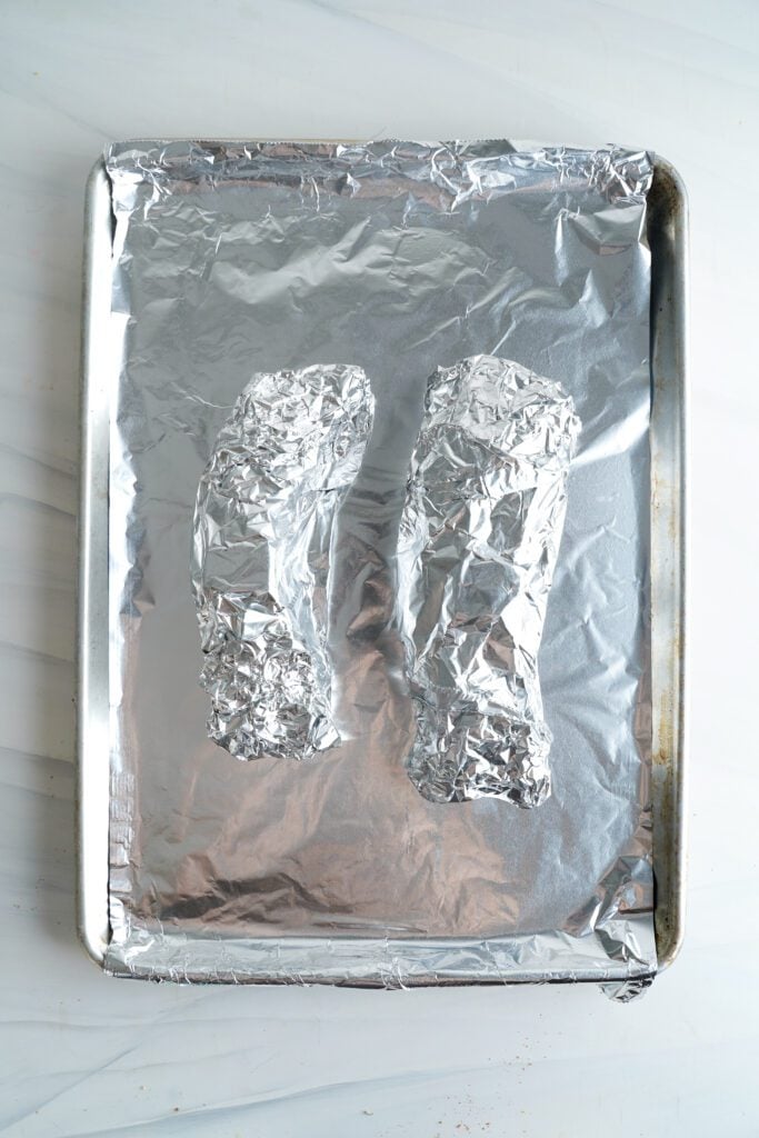 deux filets mignons de porc enveloppés dans du papier aluminium sur une plaque de cuisson | cookingwithcassandra.com