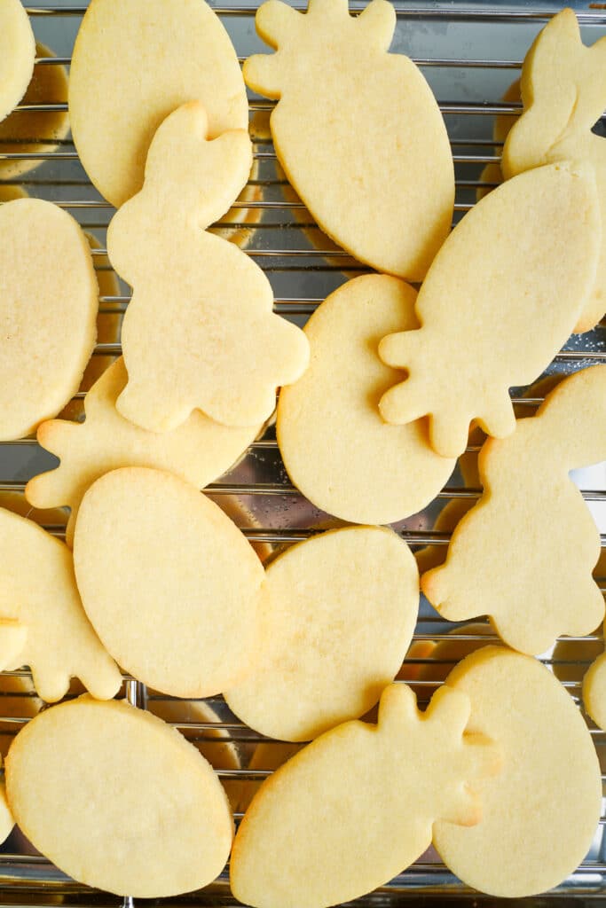 Biscuits de Pâques fraîchement cuits sous forme de lapin, de carotte et d'œuf refroidissant sur une grille.