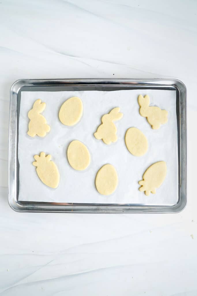 Biscuits de Pâques cuits sur une plaque de cuisson recouverte de papier sulfurisé.