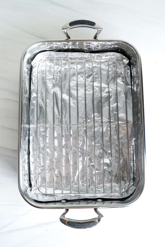 Plat de cuisson vide tapissé de papier aluminium et équipé d'une grille, prêt à cuire le jambon